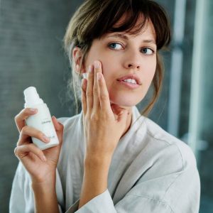 mujer aplicando crema en su cara