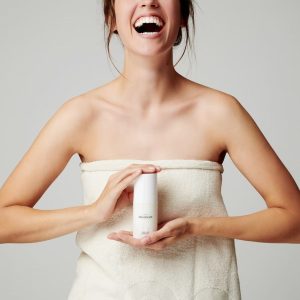 mujer sonriendo mostrando producto para el cuidado