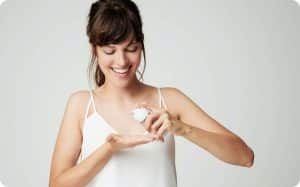 Mujer con ropa blanca aplicando crema en sus manos